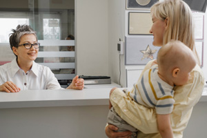 Mother and child interacting with front desk team member in dental office