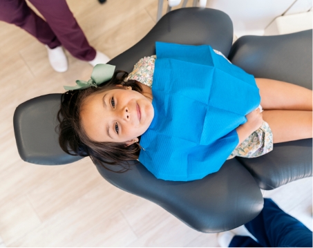 Young girl in dental chair looking at up the camera
