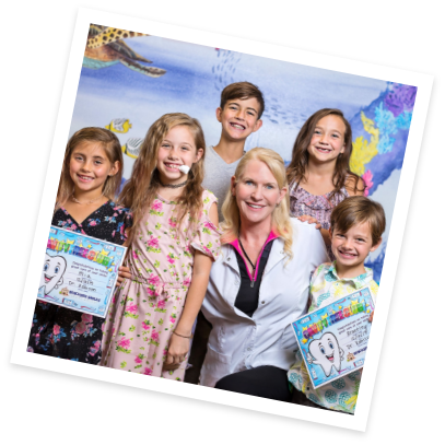 Satellite Beach pediatric dentist smiling with several kids holding certificates