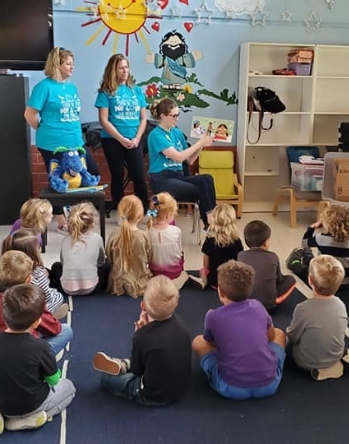 Classroom of kids listening to dental team member read a picture book