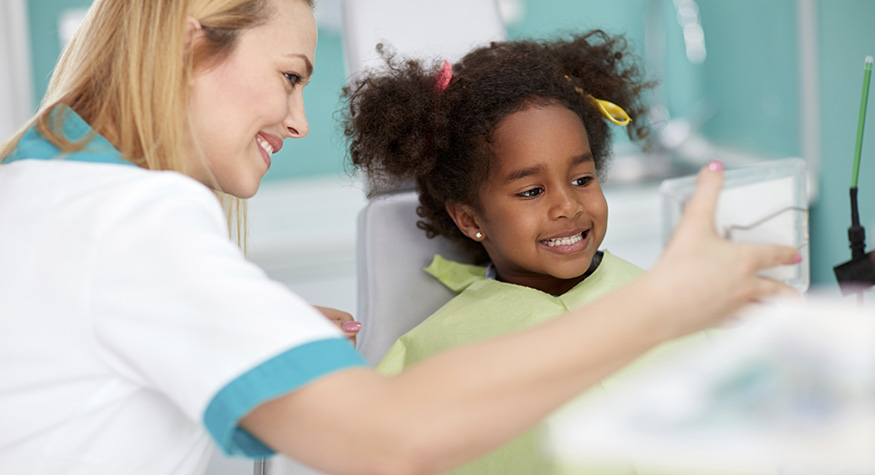 Pediatric dentist showing a child their smile in a mirror