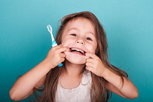 Child makes silly face while holding toothbrush