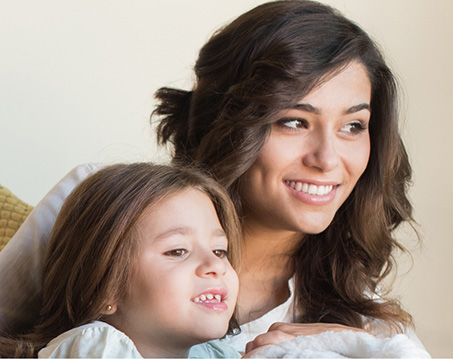 Woman with curly brown hair smiling with her daughter