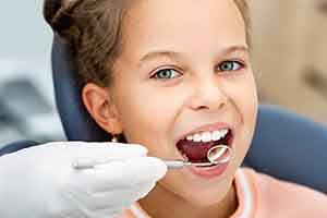 Dentist using mirror to look at child's teeth
