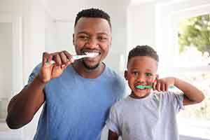 Father and son smiling while brushing their teeth