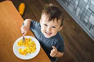 Child smiling while eating eggs