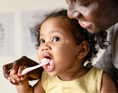 Mother showing her daughter how to brush her teeth