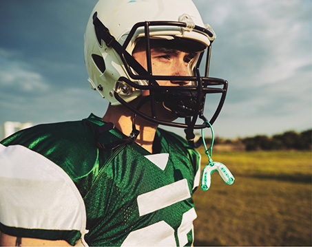 Football player with a mouthguard hanging from their helmet