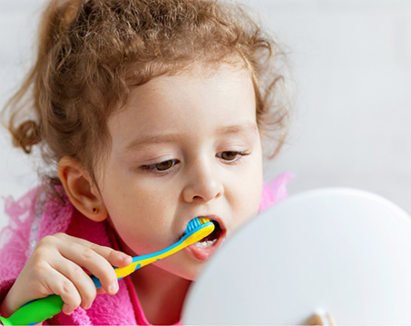 Child brushing their teeth in front of mirror