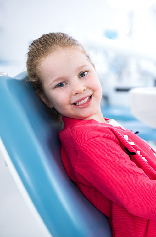 Smiling child leaning back in dental chair while visiting pediatric dentist in Satellite Beach