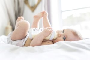 Baby on their back drinking a bottle.